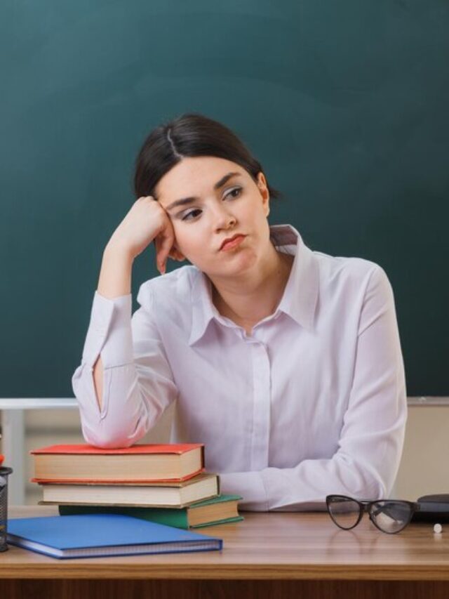 tired-putting-hand-cheek-young-female-teacher-sitting-desk-with-school-tools-classroom_141793-136649